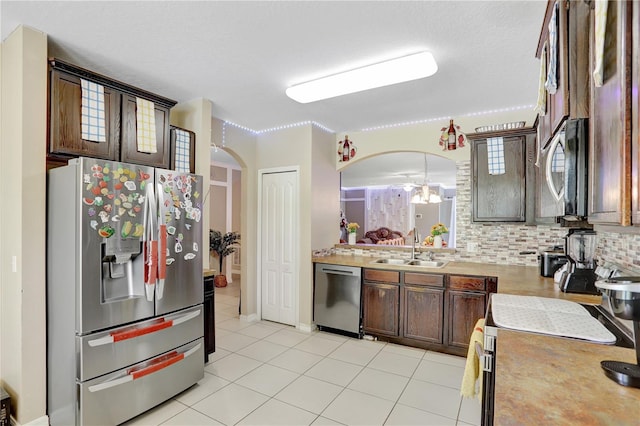 1514 Tamarind Rd, Davenport, FL 33896 - kitchen featuring stainless steel appliances, arched walkways, light countertops, decorative backsplash, and light tile patterned flooring