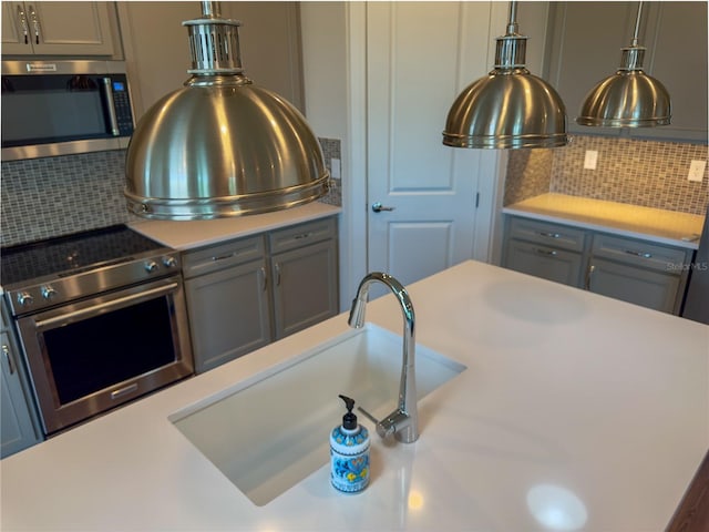 7484 Catania Loop, Clermont, FL 34714 - kitchen featuring appliances with stainless steel finishes, light countertops, backsplash, gray cabinets, and hanging light fixtures