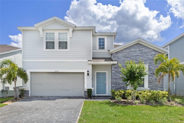 2026 Lelani Cir, Davenport, FL 33897 - view of front of home featuring stone siding, an attached garage, decorative driveway, and a front lawn