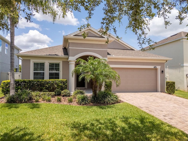 15586 Hamlin Blossom Ave, Winter Garden, FL 34787 - view of front of property featuring stucco siding, decorative driveway, an attached garage, a front lawn, and roof with shingles