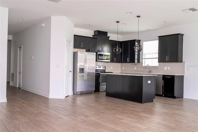 15586 Hamlin Blossom Ave, Winter Garden, FL 34787 - kitchen with appliances with stainless steel finishes, tasteful backsplash, light countertops, light wood-type flooring, and a center island