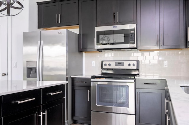 15586 Hamlin Blossom Ave, Winter Garden, FL 34787 - kitchen with stainless steel appliances, decorative backsplash, light stone countertops, and dark cabinets