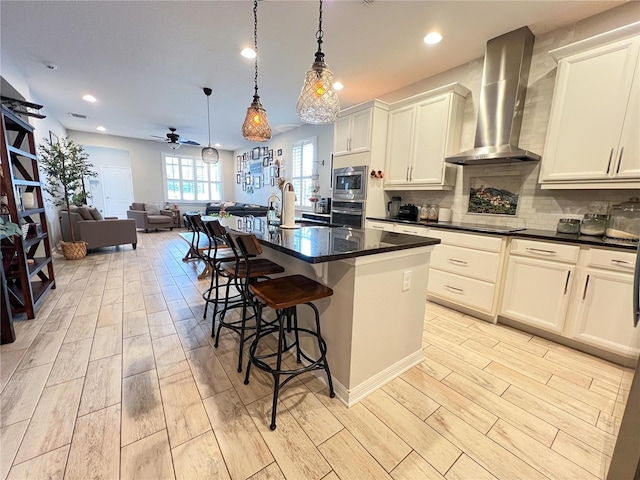 8004 Sweet Orange Ave, Winter Garden, FL 34787 - kitchen with wall chimney range hood, stainless steel appliances, ceiling fan, light wood-style floors, and recessed lighting