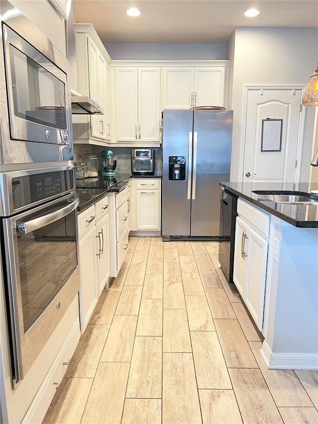 8004 Sweet Orange Ave, Winter Garden, FL 34787 - kitchen with appliances with stainless steel finishes, wood finish floors, white cabinetry, recessed lighting, and dark stone counters