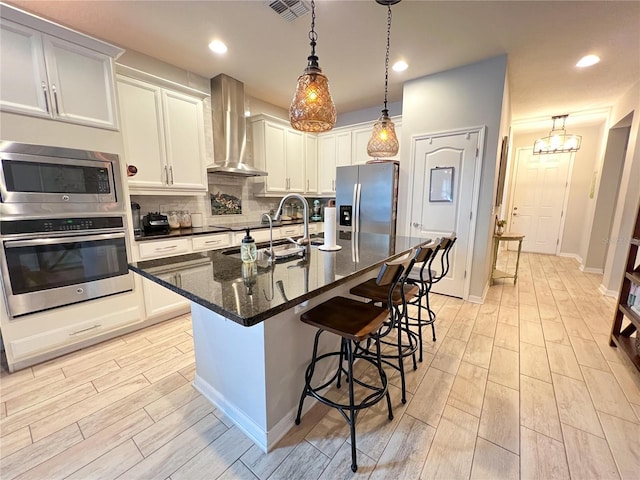 8004 Sweet Orange Ave, Winter Garden, FL 34787 - kitchen featuring appliances with stainless steel finishes, wall chimney range hood, light wood finished floors, a breakfast bar area, and backsplash