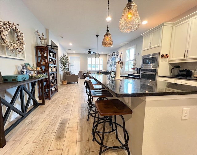 8004 Sweet Orange Ave, Winter Garden, FL 34787 - kitchen featuring appliances with stainless steel finishes, light wood-style floors, a kitchen bar, ceiling fan, and recessed lighting