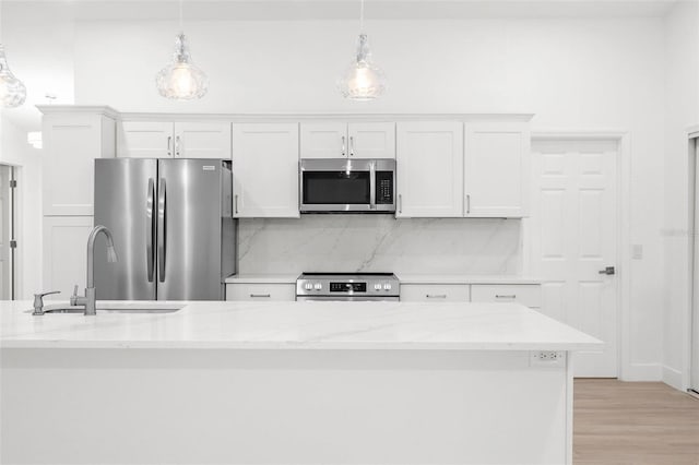 4527 Bamonte St, North Port, FL 34286 - kitchen with appliances with stainless steel finishes, white cabinetry, backsplash, hanging light fixtures, and light stone countertops