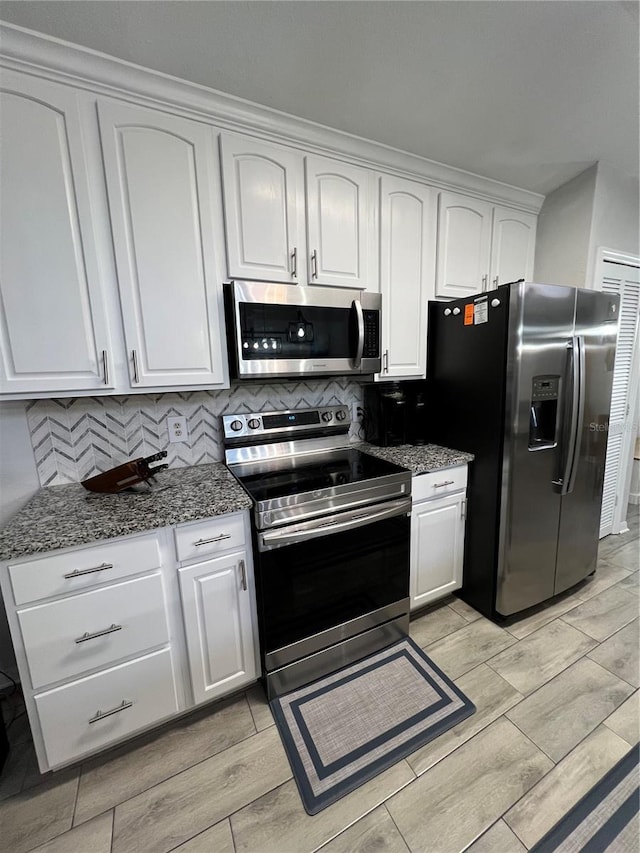 1159 E Winged Foot Cir, Winter Springs, FL 32708 - kitchen with stainless steel appliances, wood tiled floors, white cabinets, dark stone counters, and tasteful backsplash