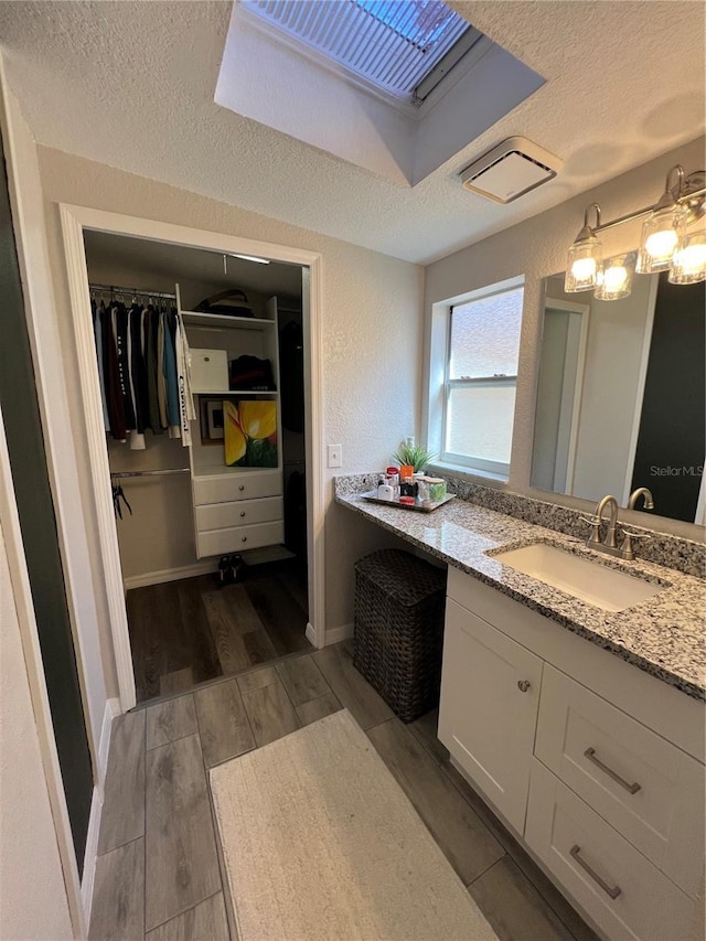 1159 E Winged Foot Cir, Winter Springs, FL 32708 - bathroom with vanity, a textured ceiling, a walk in closet, and wood finished floors