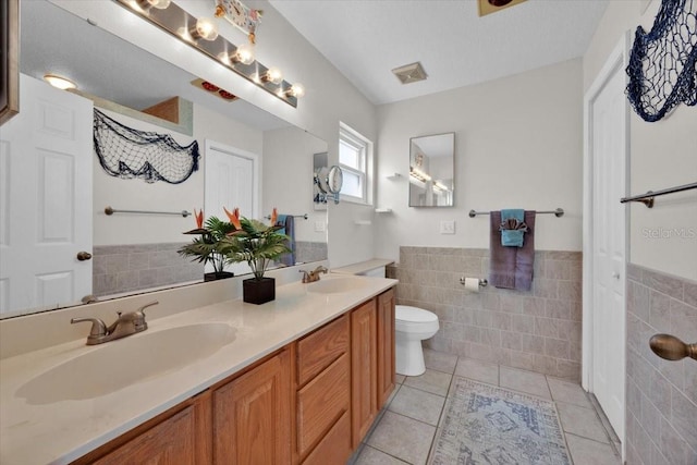 422 Harbourview Dr, Haines City, FL 33844 - bathroom featuring tile walls, tile patterned flooring, double vanity, and a wainscoted wall