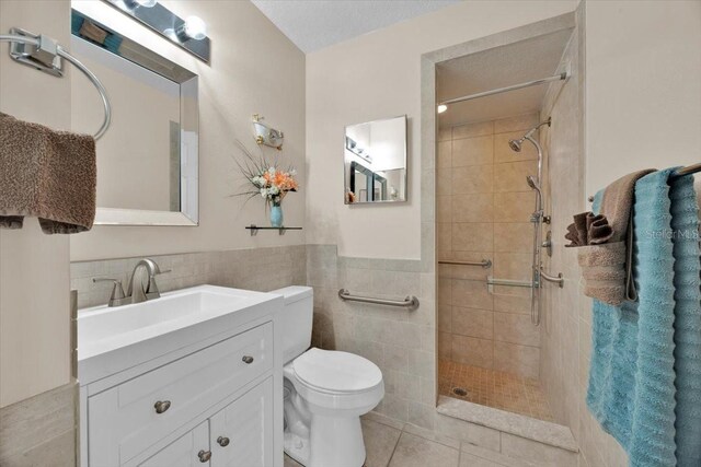 422 Harbourview Dr, Haines City, FL 33844 - full bathroom featuring tile walls, a tile shower, vanity, a wainscoted wall, and tile patterned floors
