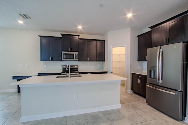 7524 Summerlake Groves St, Winter Garden, FL 34787 - kitchen featuring stainless steel appliances, decorative backsplash, light countertops, a kitchen island with sink, and light tile patterned flooring