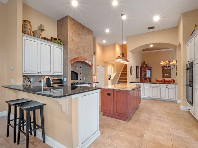 8974 Grey Hawk Pt, Orlando, FL 32836 - kitchen with a peninsula, arched walkways, backsplash, pendant lighting, and recessed lighting