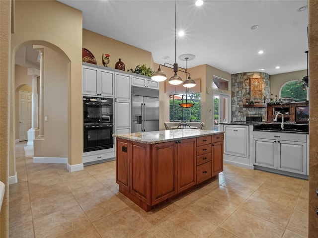 8974 Grey Hawk Pt, Orlando, FL 32836 - kitchen featuring built in refrigerator, arched walkways, a kitchen island, decorative light fixtures, and dark stone counters