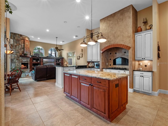 8974 Grey Hawk Pt, Orlando, FL 32836 - kitchen with light tile patterned floors, a fireplace, decorative backsplash, a center island, and black gas stovetop