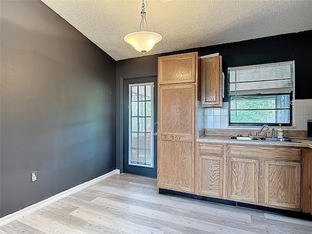1510 Chatsworth Ave, Deltona, FL 32738 - kitchen featuring a textured ceiling, backsplash, light wood-style flooring, light countertops, and pendant lighting