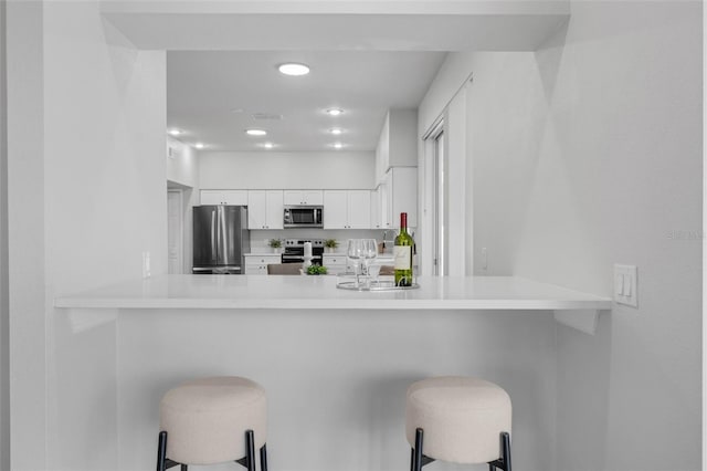1121 Needlewood Loop, Oviedo, FL 32765 - kitchen featuring stainless steel appliances, white cabinetry, a breakfast bar area, light countertops, and a peninsula