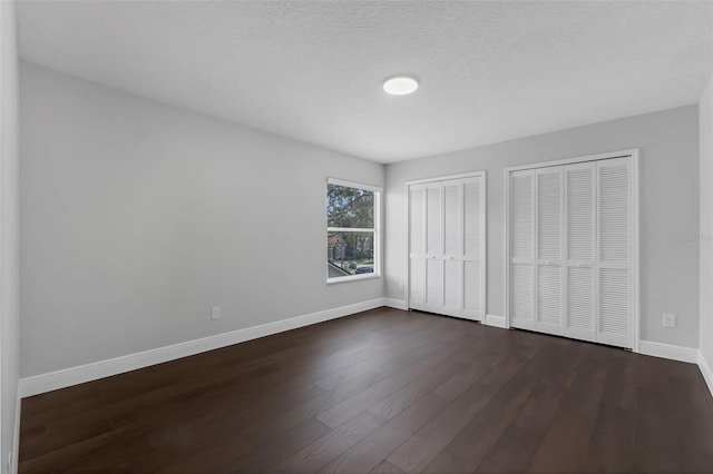 1121 Needlewood Loop, Oviedo, FL 32765 - unfurnished bedroom featuring multiple closets, dark wood-style flooring, and a textured ceiling