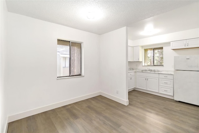 175 Springwood Cir Unit C, Longwood, FL 32750 - kitchen featuring freestanding refrigerator, light countertops, light wood-type flooring, white cabinets, and a textured ceiling