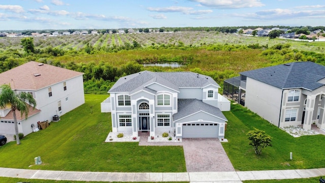 5209 Cape Hatteras Dr, Clermont, FL 34714 - view of front facade with decorative driveway, a shingled roof, a front lawn, an attached garage, and glass enclosure