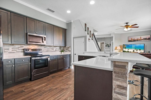 5209 Cape Hatteras Dr, Clermont, FL 34714 - kitchen featuring stainless steel appliances, open floor plan, backsplash, dark wood finished floors, and a kitchen breakfast bar