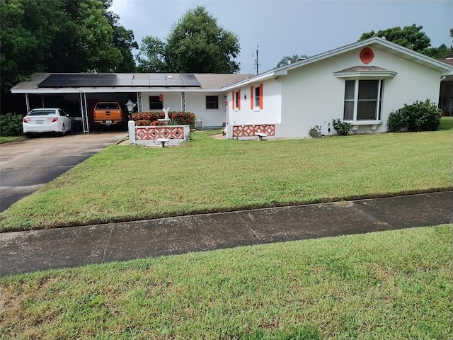 4427 Gilpin Way, Orlando, FL 32812 - ranch-style home featuring stucco siding, a front yard, concrete driveway, roof mounted solar panels, and a carport