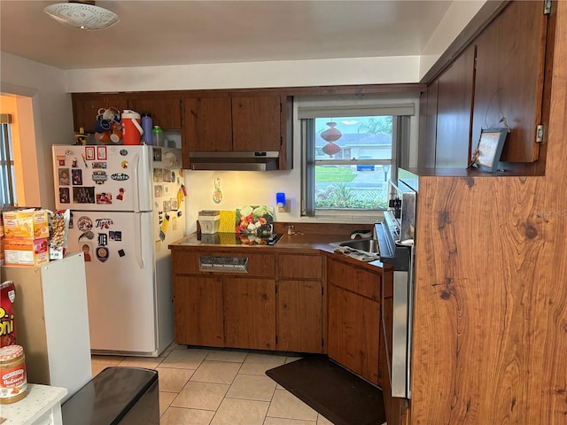 4427 Gilpin Way, Orlando, FL 32812 - kitchen featuring under cabinet range hood, freestanding refrigerator, light tile patterned floors, dark countertops, and black electric cooktop