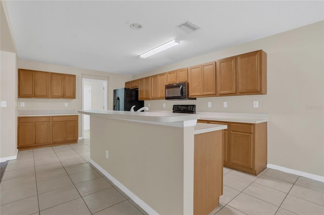 316 Crichton St, Ruskin, FL 33570 - kitchen with black appliances, light tile patterned floors, light countertops, and a center island with sink