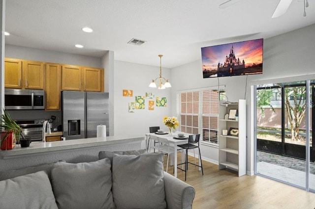 2426 Caravelle Cir, Kissimmee, FL 34746 - kitchen with stainless steel appliances, light wood-style flooring, open floor plan, recessed lighting, and a chandelier