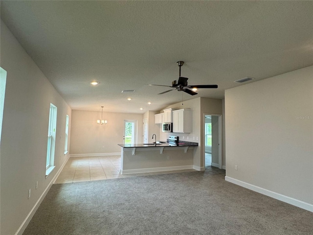 4038 Sagefield Dr, Harmony, FL 34773 - kitchen with light colored carpet, a kitchen breakfast bar, stainless steel microwave, white cabinetry, and stove