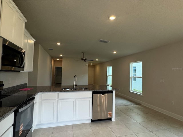 4038 Sagefield Dr, Harmony, FL 34773 - kitchen featuring stainless steel appliances, a ceiling fan, a peninsula, white cabinetry, and dark stone countertops
