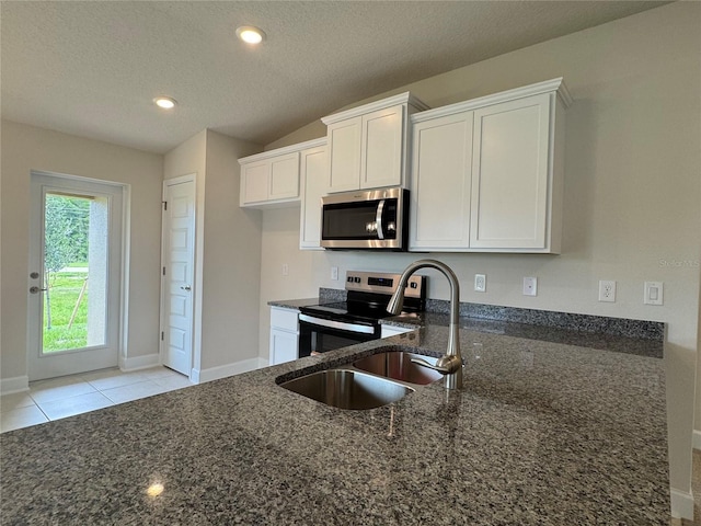 4038 Sagefield Dr, Harmony, FL 34773 - kitchen featuring stainless steel appliances, dark stone countertops, white cabinetry, a textured ceiling, and light tile patterned floors