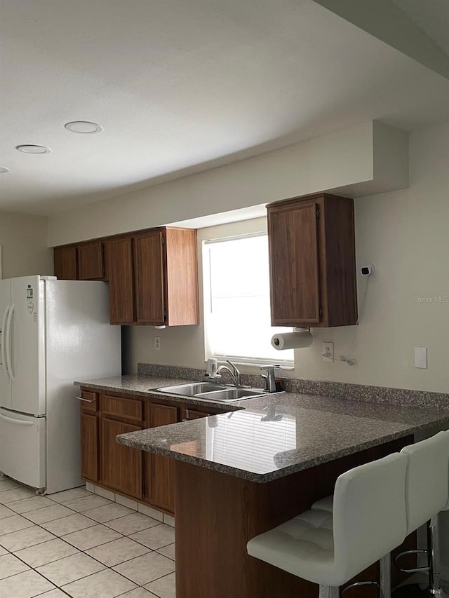 532 Koala Dr, Kissimmee, FL 34759 - kitchen with freestanding refrigerator, a peninsula, light tile patterned flooring, and a breakfast bar area