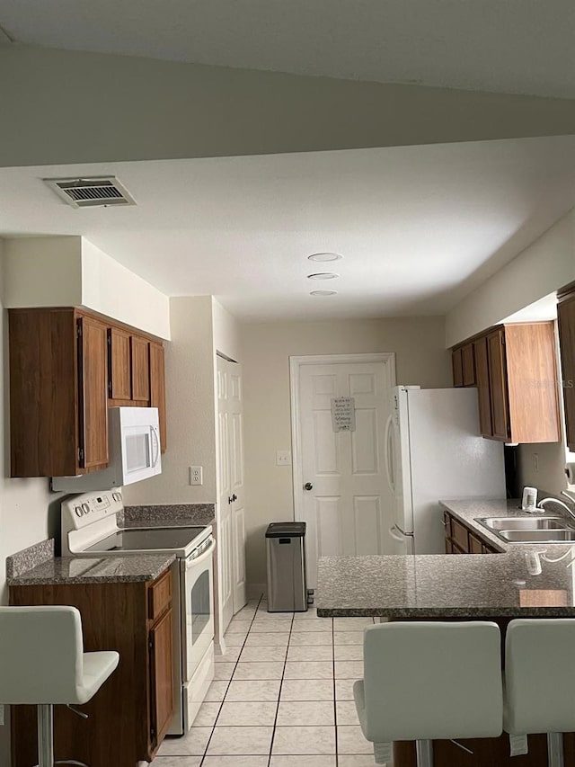 532 Koala Dr, Kissimmee, FL 34759 - kitchen featuring white appliances, light tile patterned floors, dark countertops, and a peninsula
