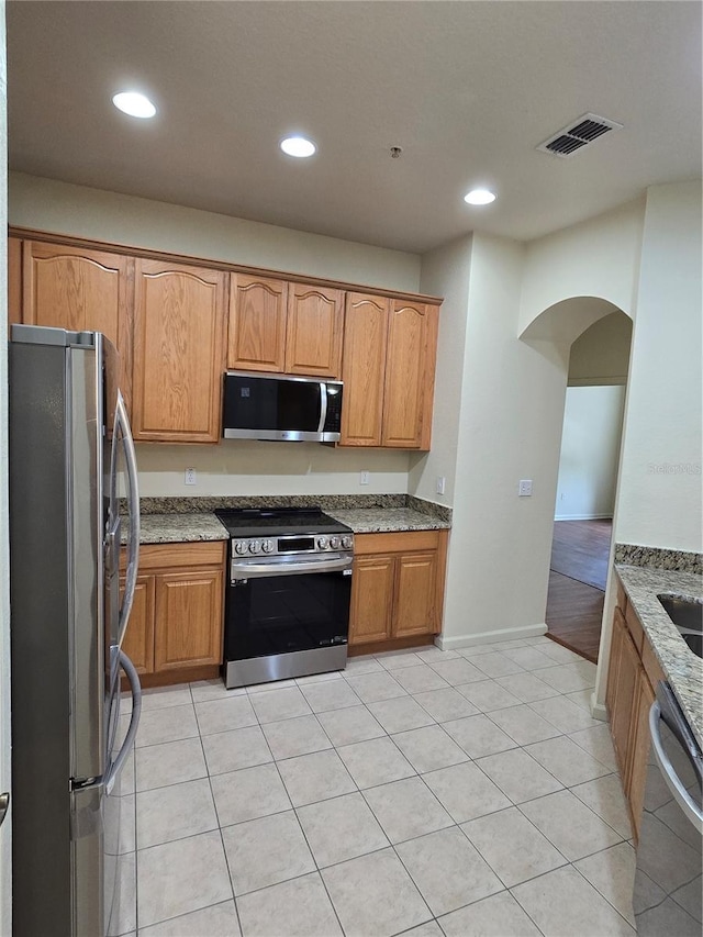 3001 Laurel Run Ln Unit 203, Kissimmee, FL 34741 - kitchen with appliances with stainless steel finishes, arched walkways, light stone counters, recessed lighting, and light tile patterned floors