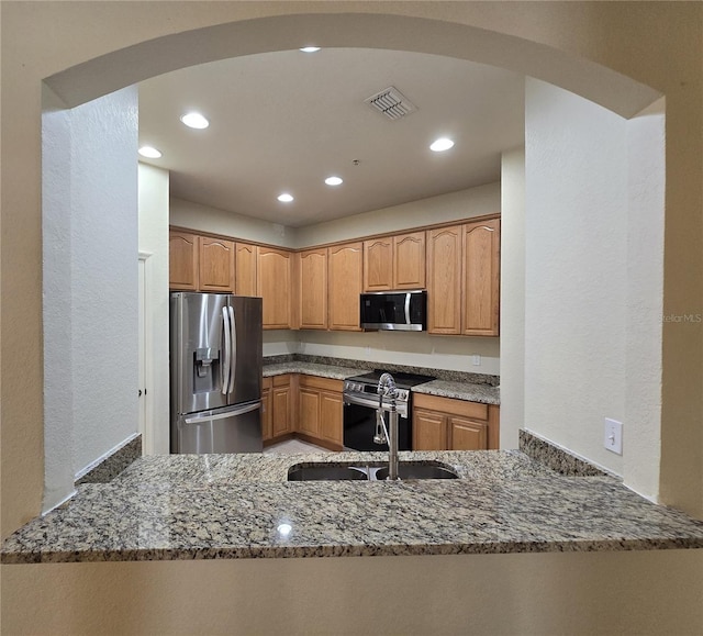 3001 Laurel Run Ln Unit 203, Kissimmee, FL 34741 - kitchen with appliances with stainless steel finishes, dark stone counters, arched walkways, a textured wall, and recessed lighting