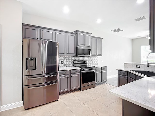 11127 Irish Moss Ave, Riverview, FL 33569 - kitchen with stainless steel appliances, gray cabinets, backsplash, light tile patterned flooring, and light stone countertops
