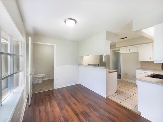 1215 Merlyn St, Lakeland, FL 33813 - kitchen featuring white cabinets, light countertops, a peninsula, and light wood-style flooring