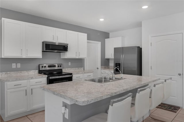 1296 Berry Ln, Davenport, FL 33837 - kitchen with appliances with stainless steel finishes, light tile patterned floors, white cabinetry, light countertops, and a center island with sink