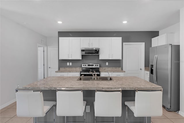 1296 Berry Ln, Davenport, FL 33837 - kitchen featuring appliances with stainless steel finishes, light tile patterned floors, a center island with sink, white cabinetry, and recessed lighting