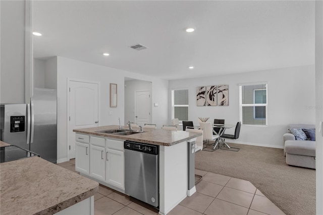 1296 Berry Ln, Davenport, FL 33837 - kitchen with appliances with stainless steel finishes, light carpet, open floor plan, white cabinetry, and light tile patterned flooring