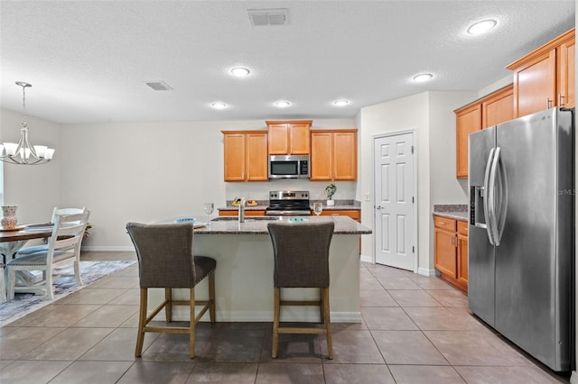 1330 Bucktail Ct, Kissimmee, FL 34746 - kitchen with stainless steel appliances, tile patterned floors, a chandelier, an island with sink, and a textured ceiling