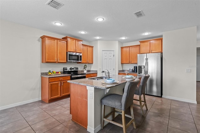 1330 Bucktail Ct, Kissimmee, FL 34746 - kitchen with appliances with stainless steel finishes, a kitchen breakfast bar, brown cabinets, recessed lighting, and a textured ceiling
