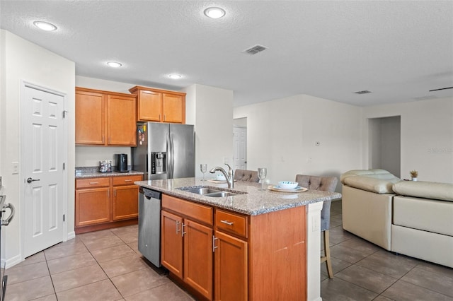 1330 Bucktail Ct, Kissimmee, FL 34746 - kitchen featuring stainless steel appliances, open floor plan, a kitchen breakfast bar, light tile patterned floors, and light stone countertops