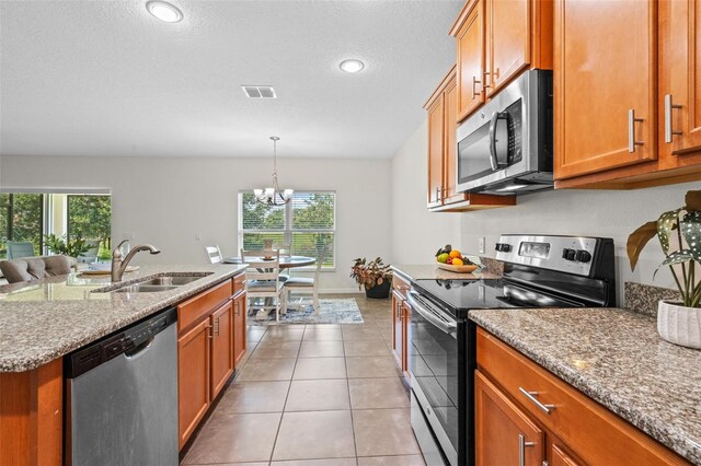 1330 Bucktail Ct, Kissimmee, FL 34746 - kitchen with stainless steel appliances, brown cabinets, plenty of natural light, a chandelier, and recessed lighting