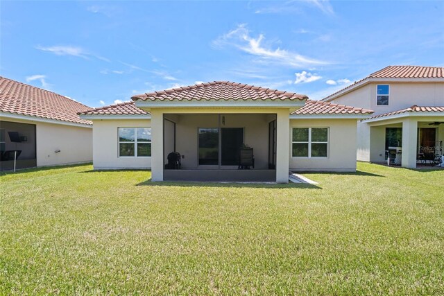 1330 Bucktail Ct, Kissimmee, FL 34746 - back of house with a tiled roof, a lawn, a sunroom, and stucco siding
