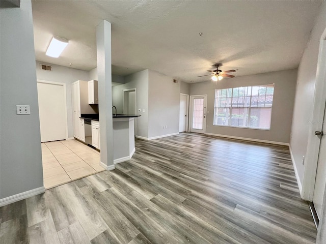 5566 Metrowest Blvd Unit 2-105, Orlando, FL 32811 - unfurnished living room featuring ceiling fan, light wood-type flooring, and a textured ceiling