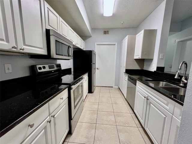 5566 Metrowest Blvd Unit 2-105, Orlando, FL 32811 - kitchen with appliances with stainless steel finishes, white cabinets, light tile patterned floors, and a textured ceiling