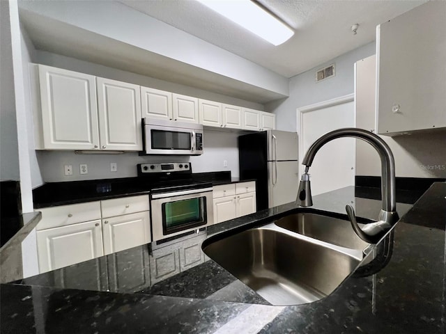 5566 Metrowest Blvd Unit 2-105, Orlando, FL 32811 - kitchen featuring stainless steel appliances, white cabinetry, and dark stone countertops