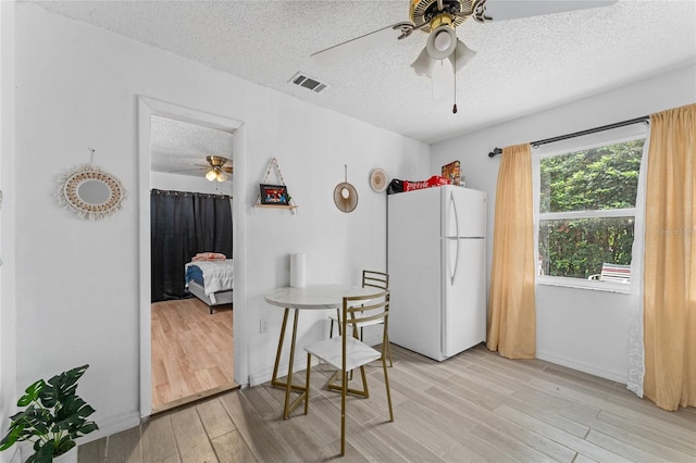 2666 Capp Cir, Kissimmee, FL 34744 - kitchen with freestanding refrigerator, ceiling fan, a textured ceiling, and light wood-style floors